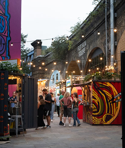 Small groups of people talking and enjoying street food at an outdoor market.