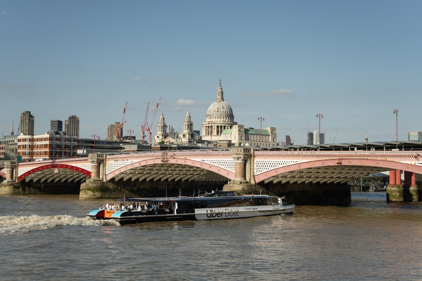 The River Thames with an Uber Boat sailing under a bridge near Bankside.